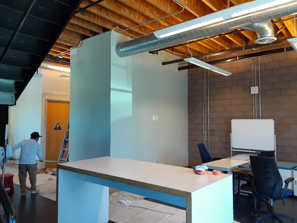 A man is painting a wall in an office