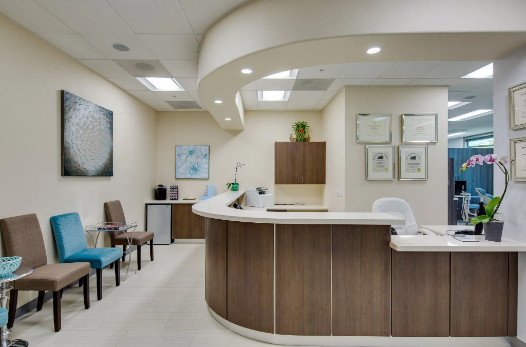 A waiting room with a reception desk and chairs.