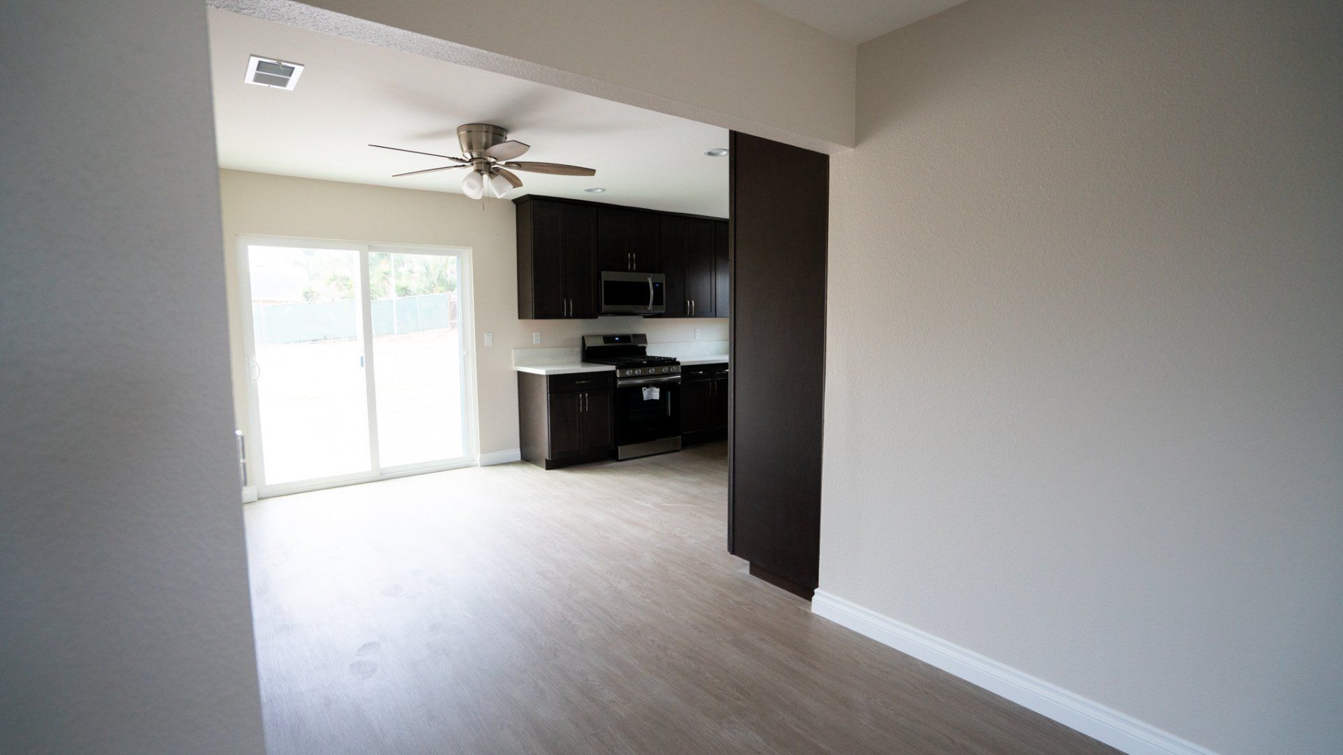 An empty room with a kitchen and a ceiling fan