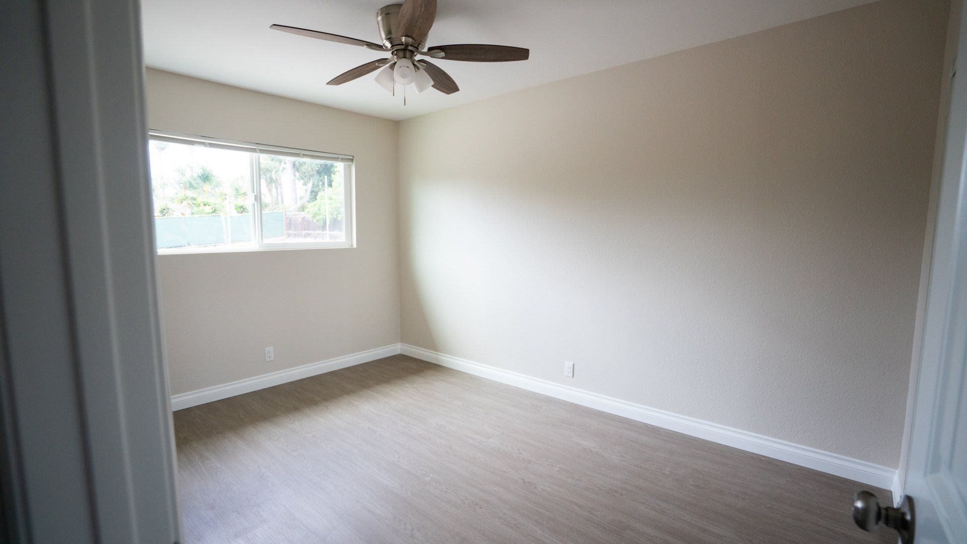 An empty bedroom with a ceiling fan and a window