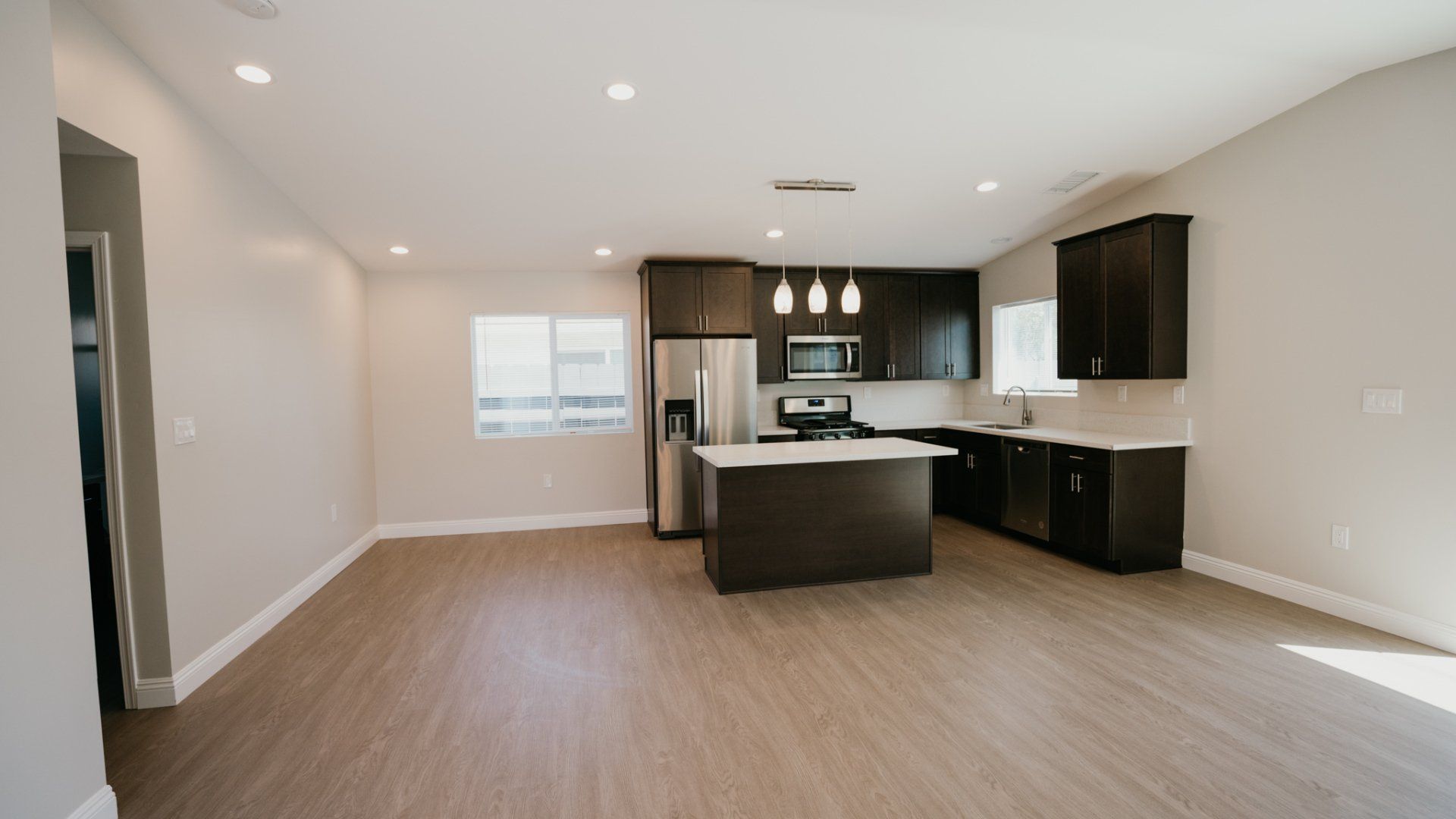 An empty kitchen with a large island and stainless steel appliances