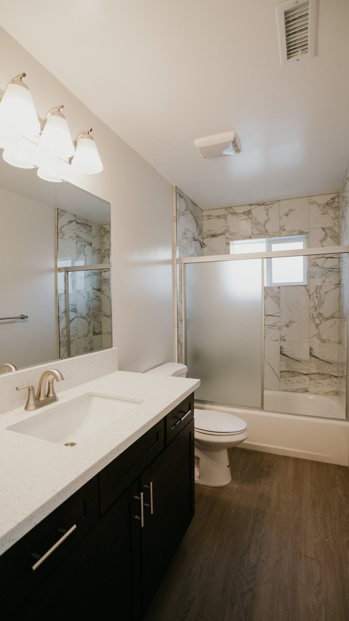 A bathroom with a sink , toilet , shower and mirror.