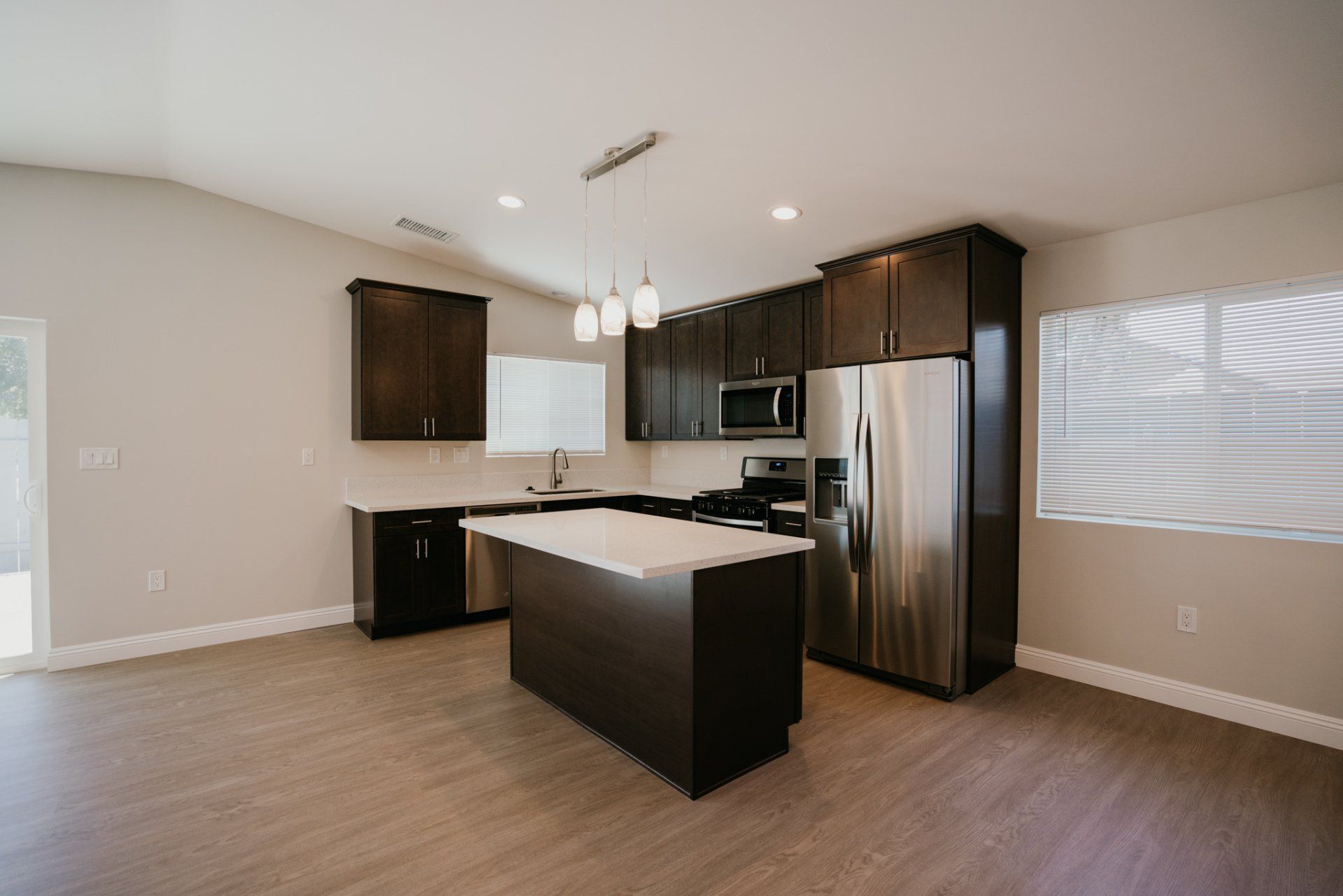 An empty kitchen with stainless steel appliances and a large island.