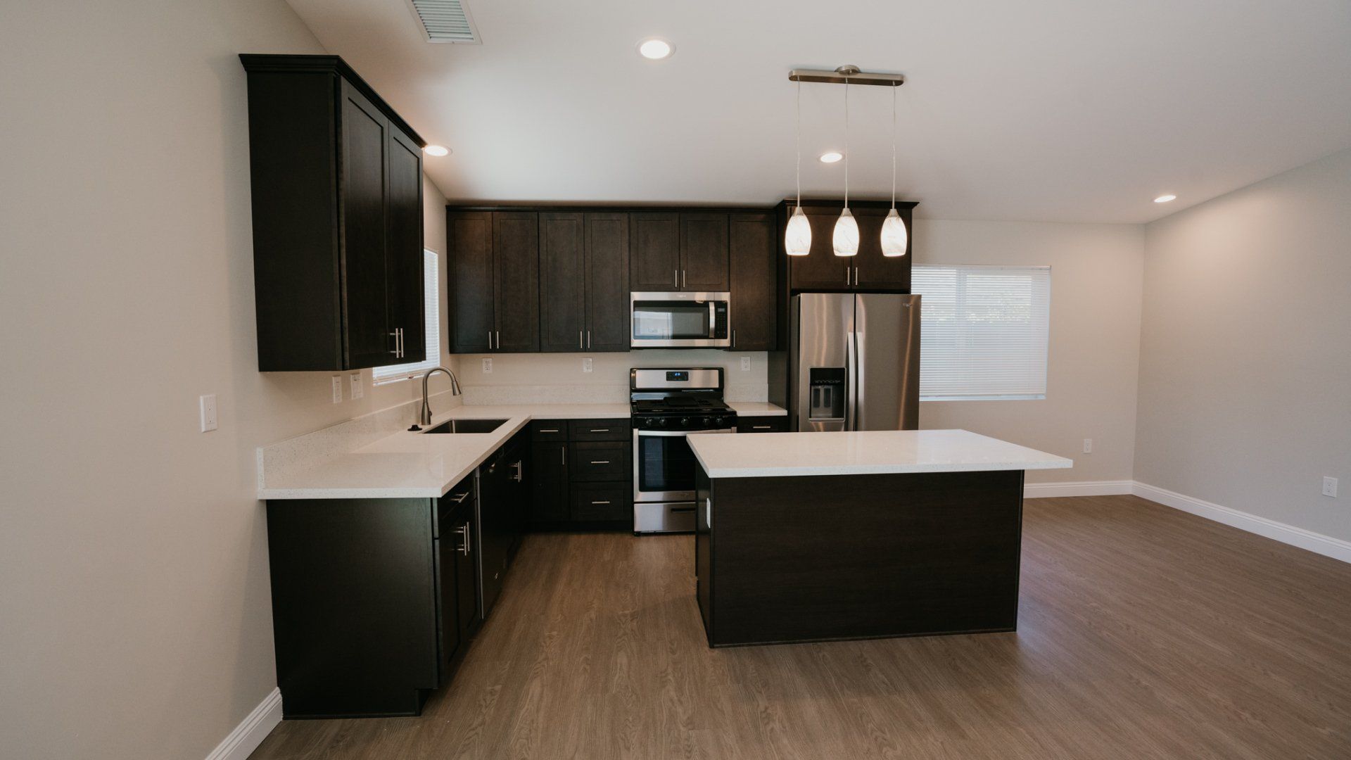 An empty kitchen with black cabinets and stainless steel appliances.