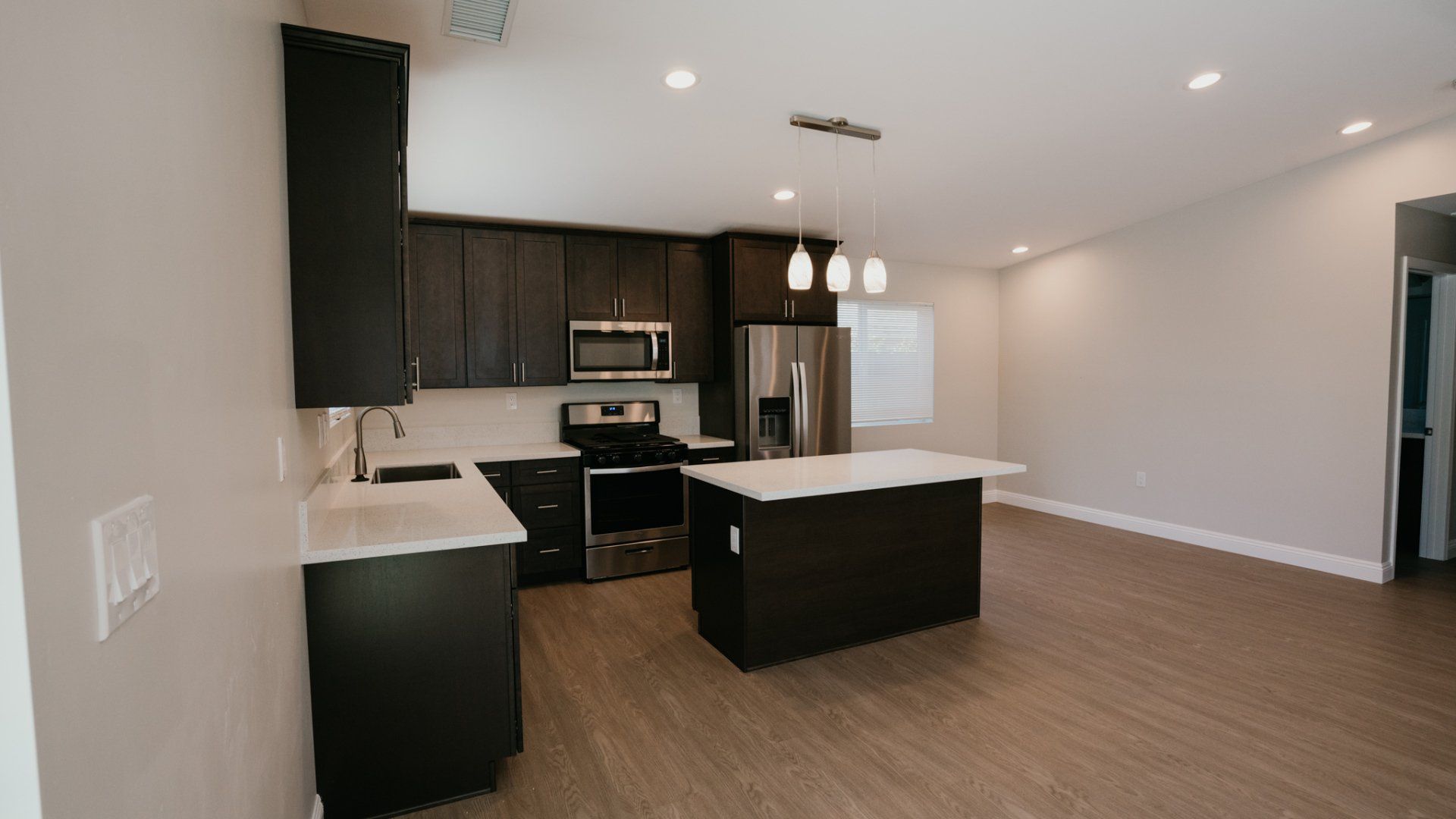 A kitchen with black cabinets , stainless steel appliances , and a large island.
