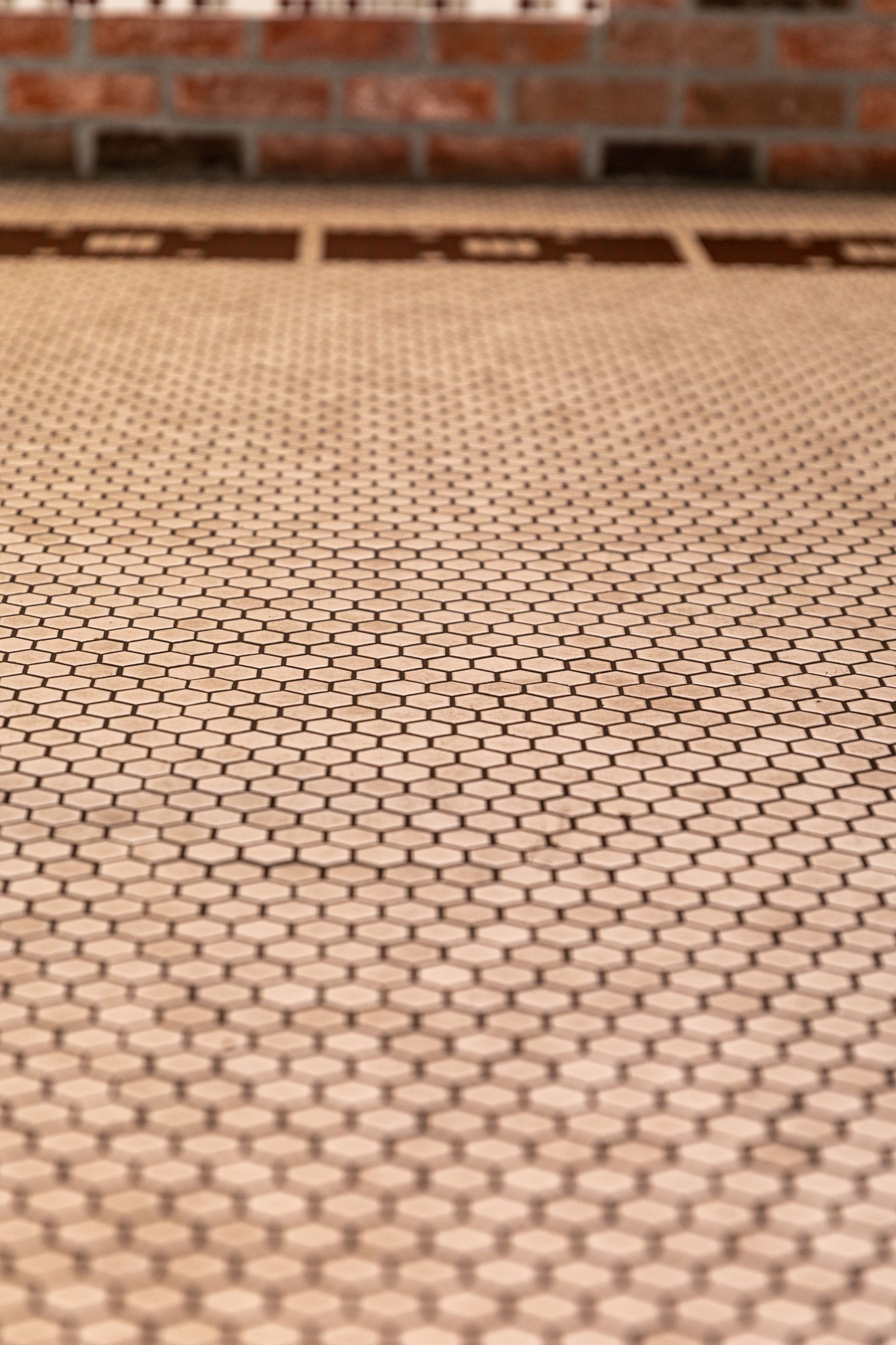 A close up of a tile floor with a brick wall in the background.