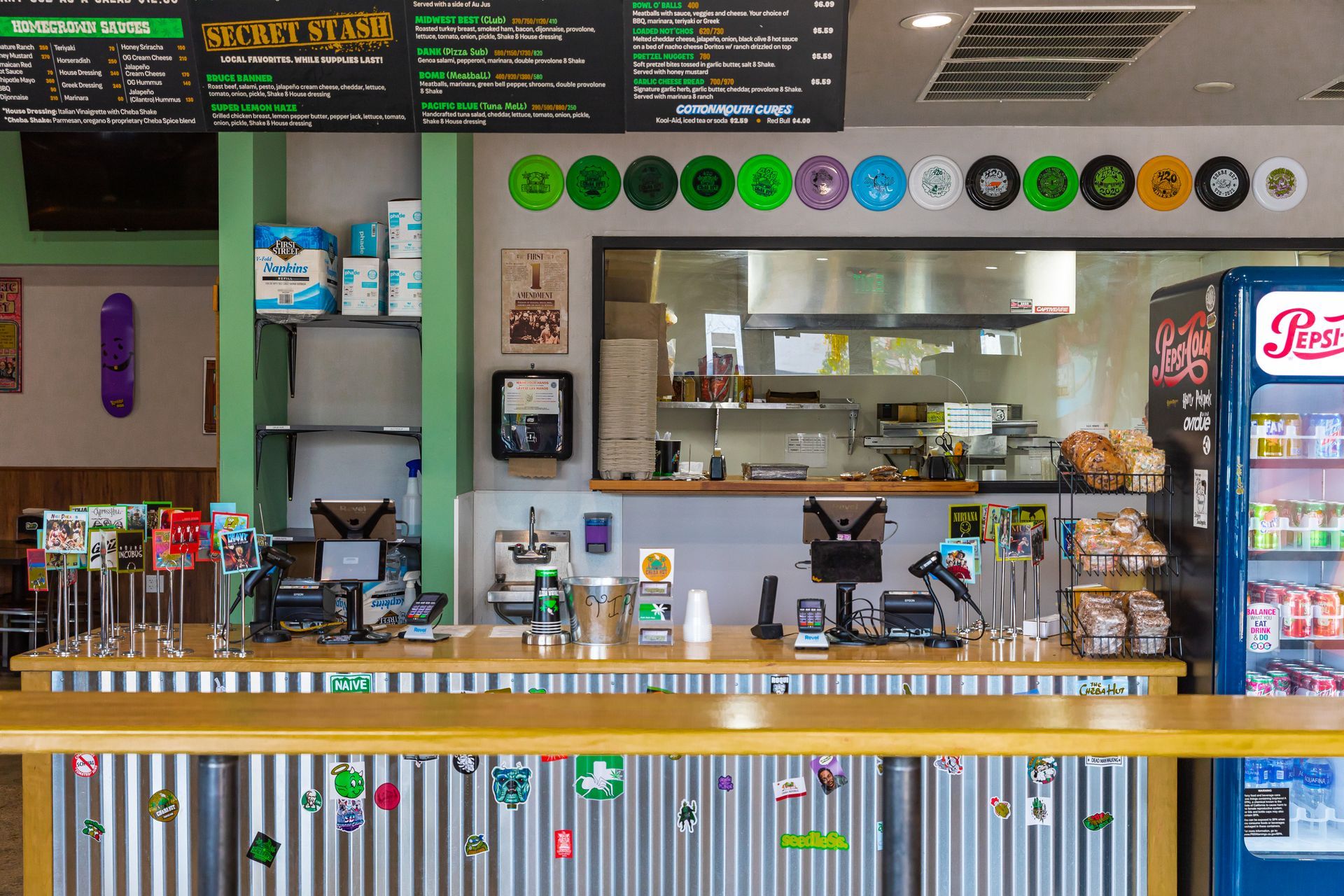 The inside of a restaurant with a pepsi refrigerator and a counter.