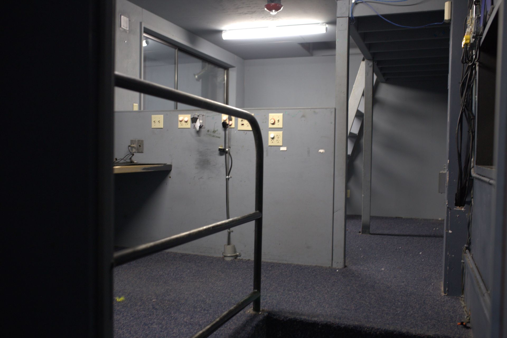 A dark room with a metal railing and a staircase