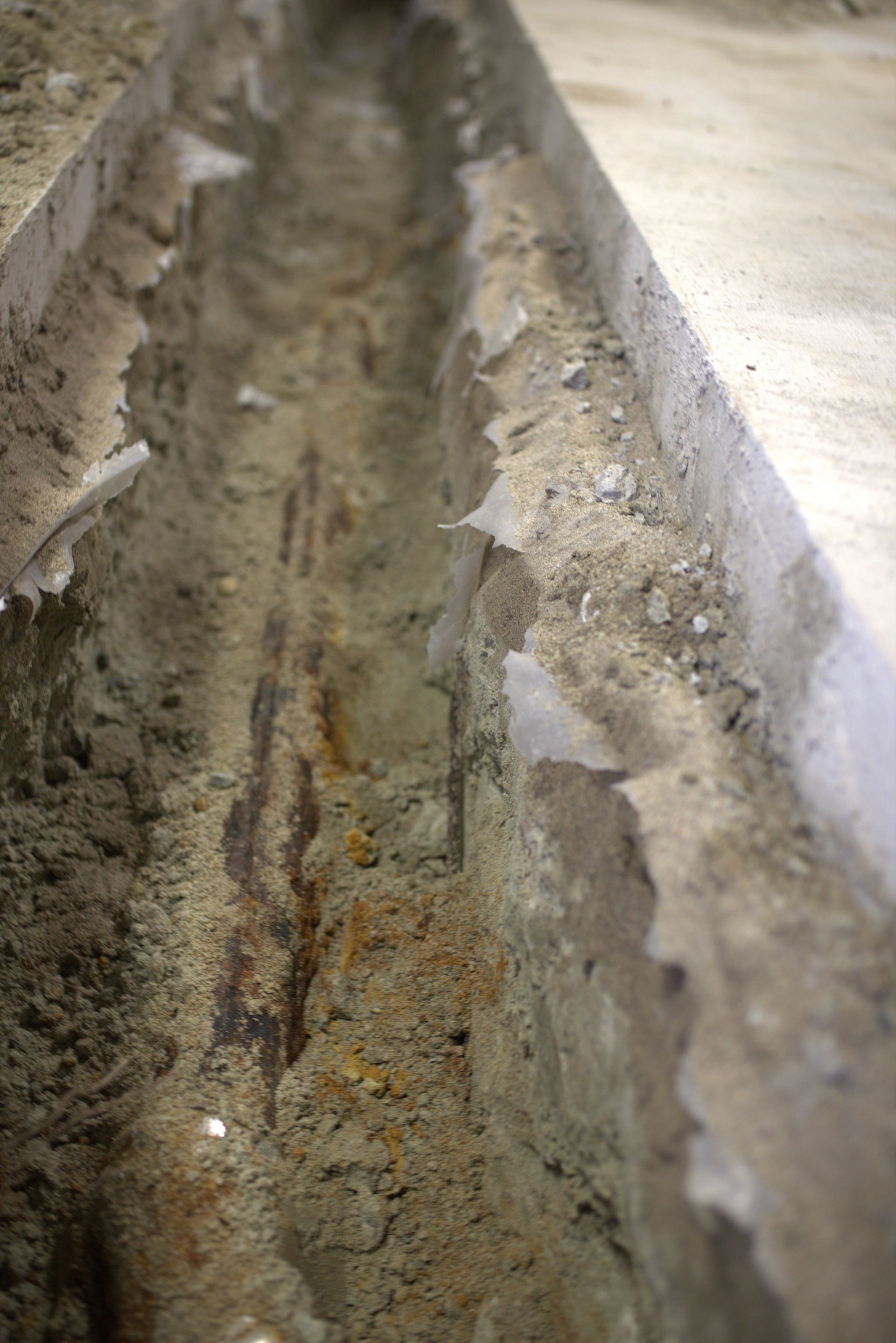 A close up of a concrete drain on a wooden floor.