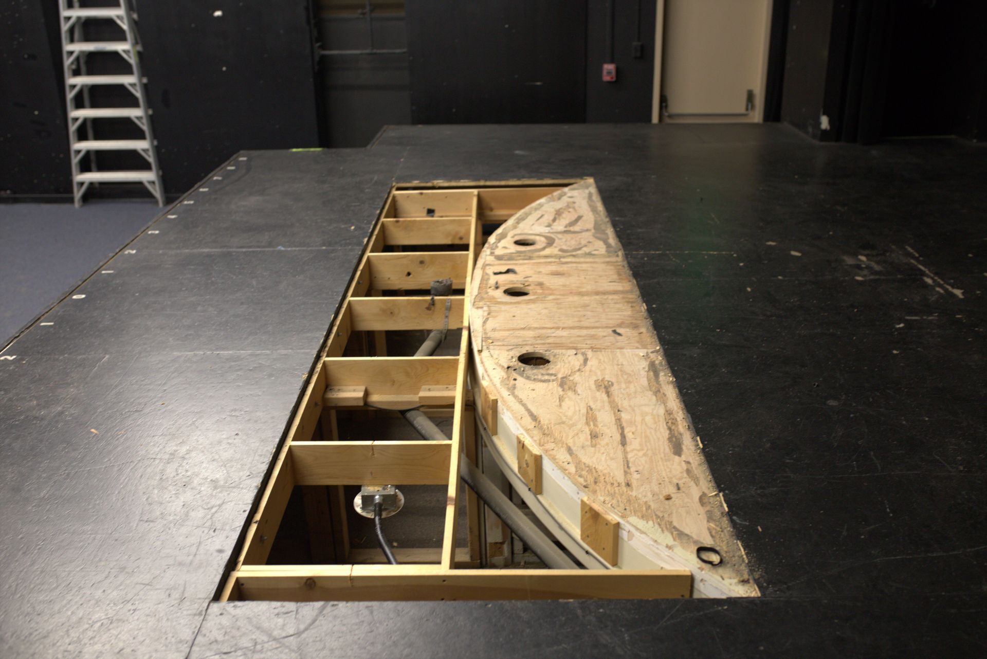 A hole in the floor with a ladder in the background