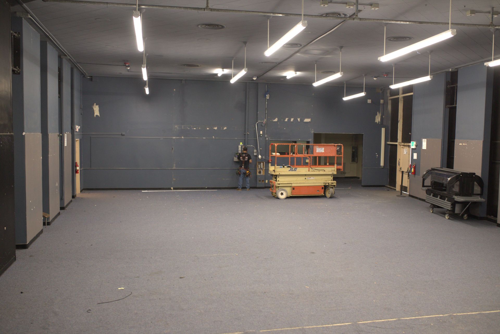 A large empty room with a jlg scissor lift in the middle