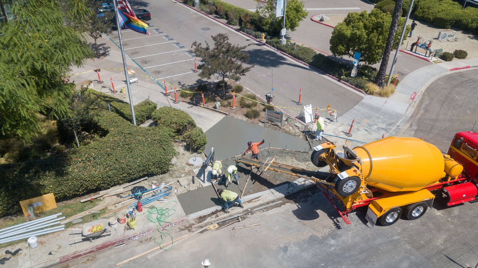 An aerial view of a concrete mixer truck pouring concrete on a street.