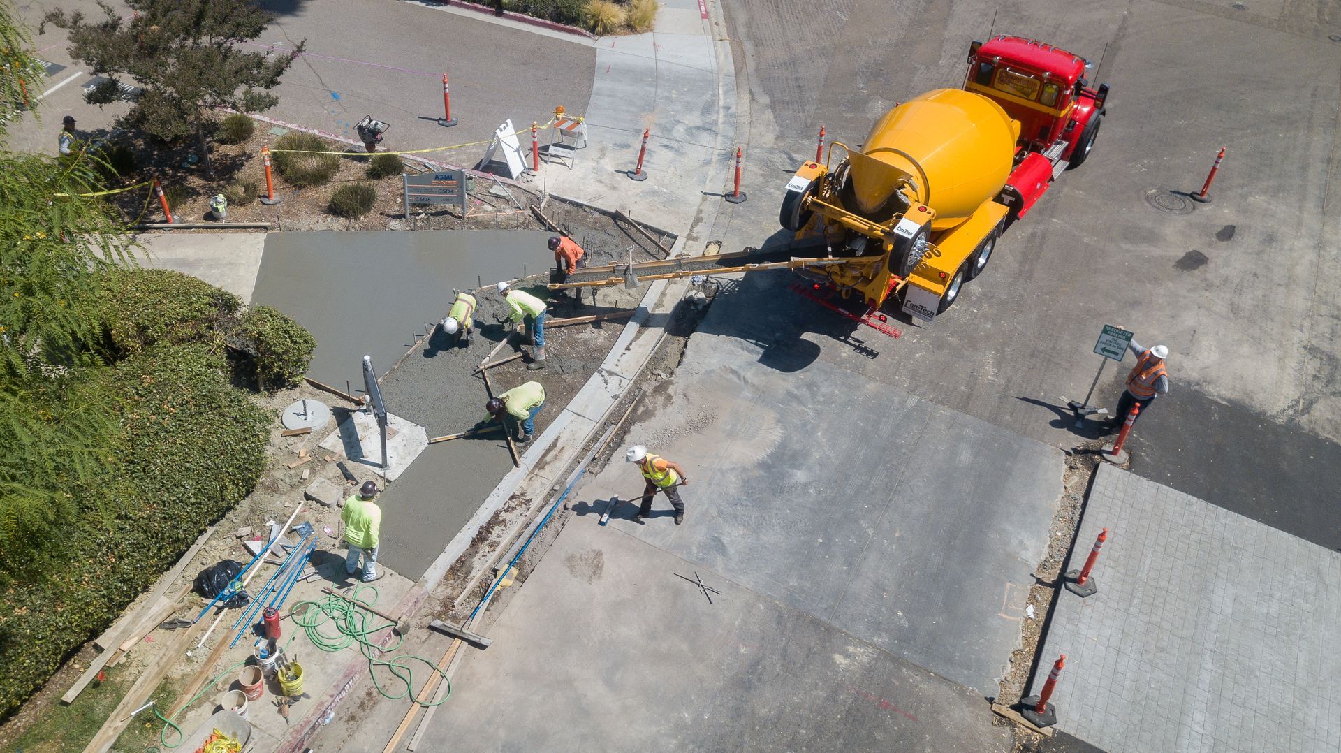 An aerial view of a concrete mixer truck pouring concrete into a driveway.