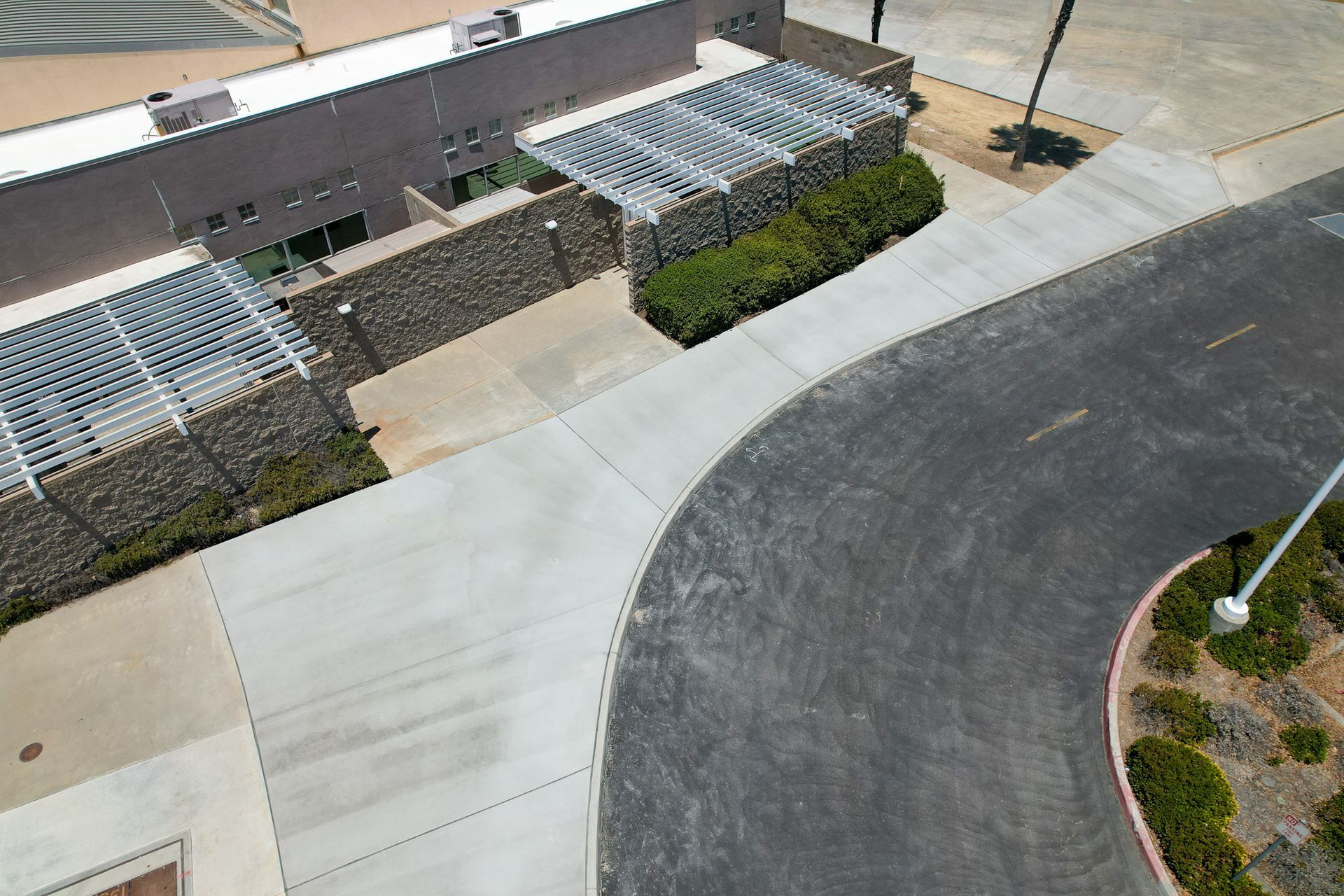 Aerial view of a curved residential street beside a building with awnings and landscaped shrubs
