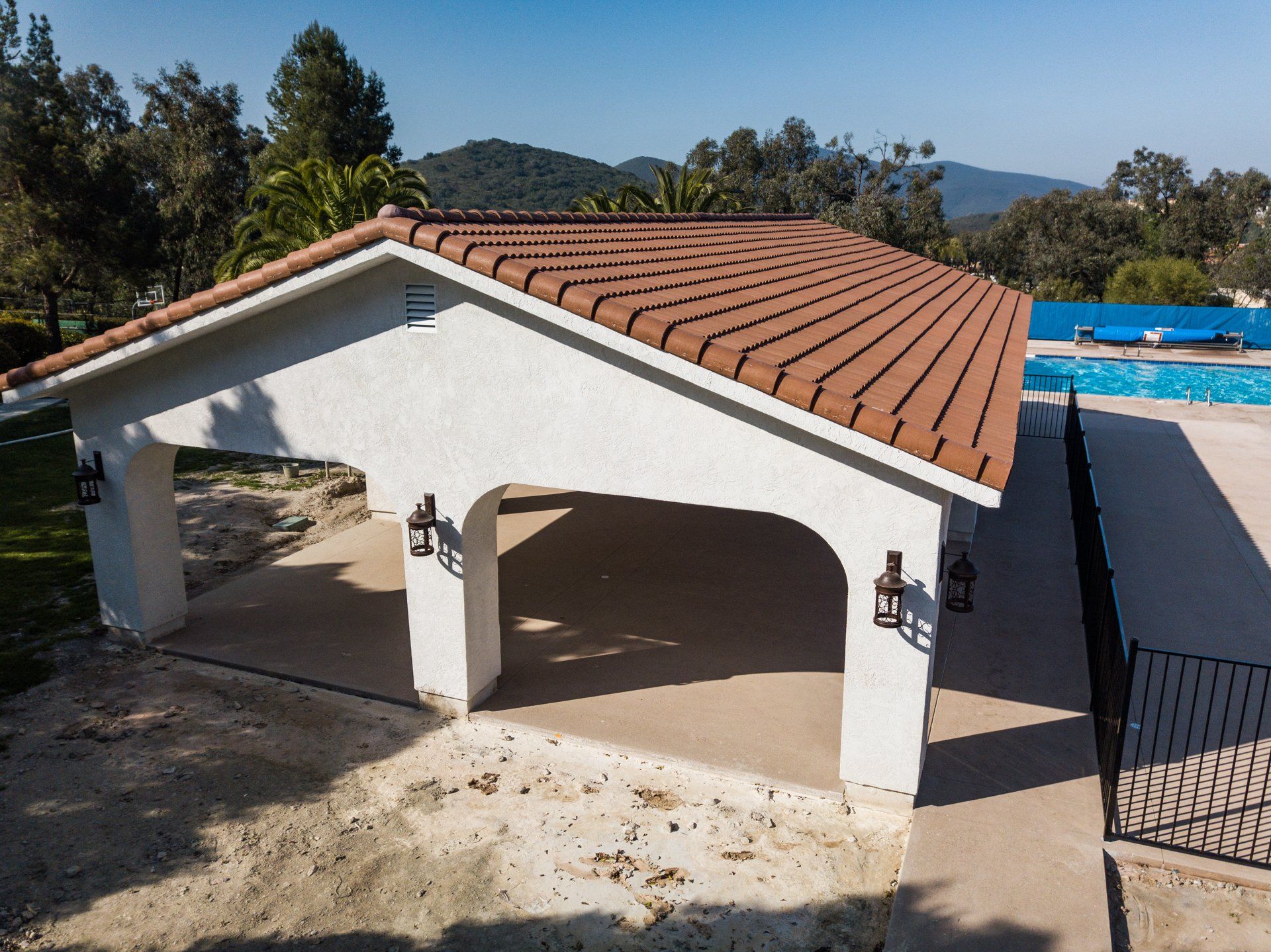 A white building with a red tile roof next to a pool