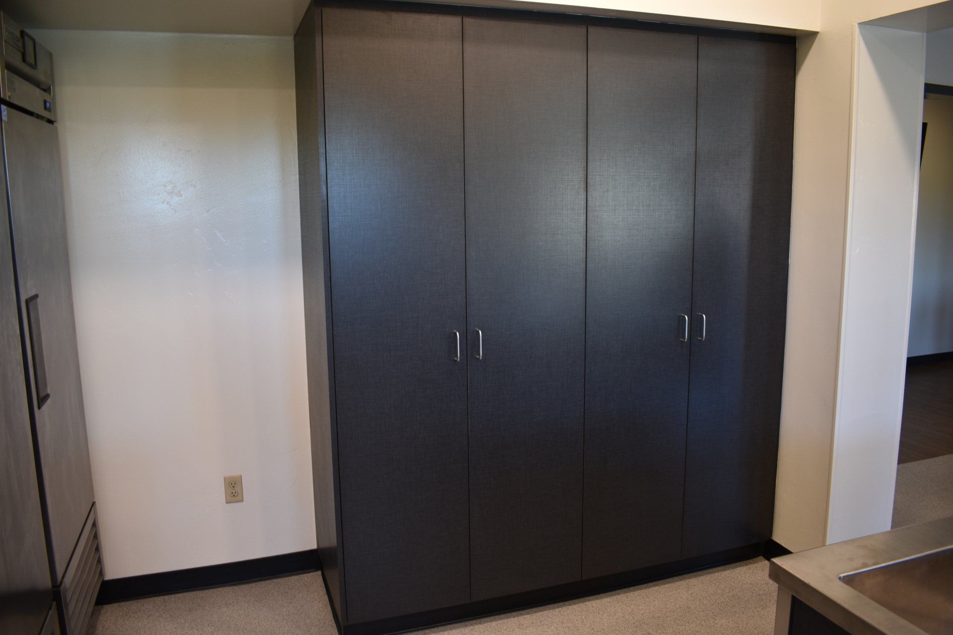 A kitchen with a stainless steel refrigerator and black cabinets