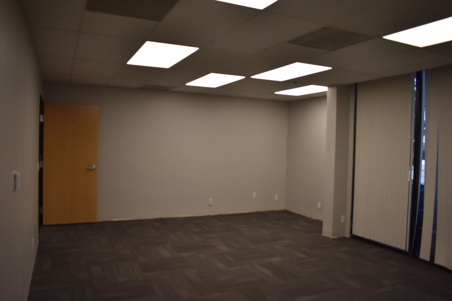 An empty room with a door and blinds on the windows
