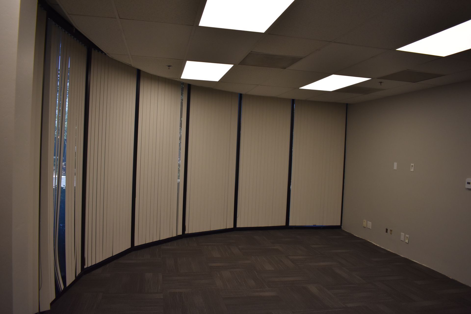 An empty room with a curved wall and blinds