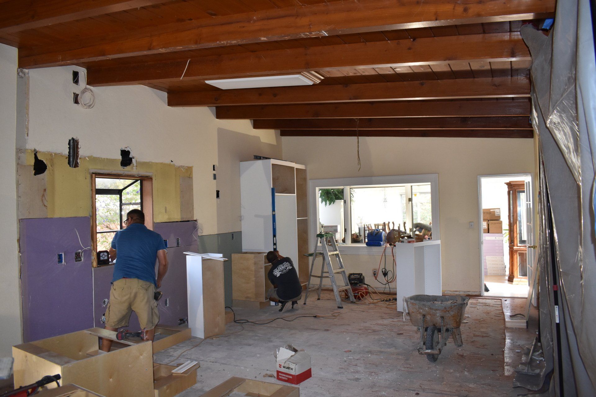 A man in a blue shirt is working on a kitchen
