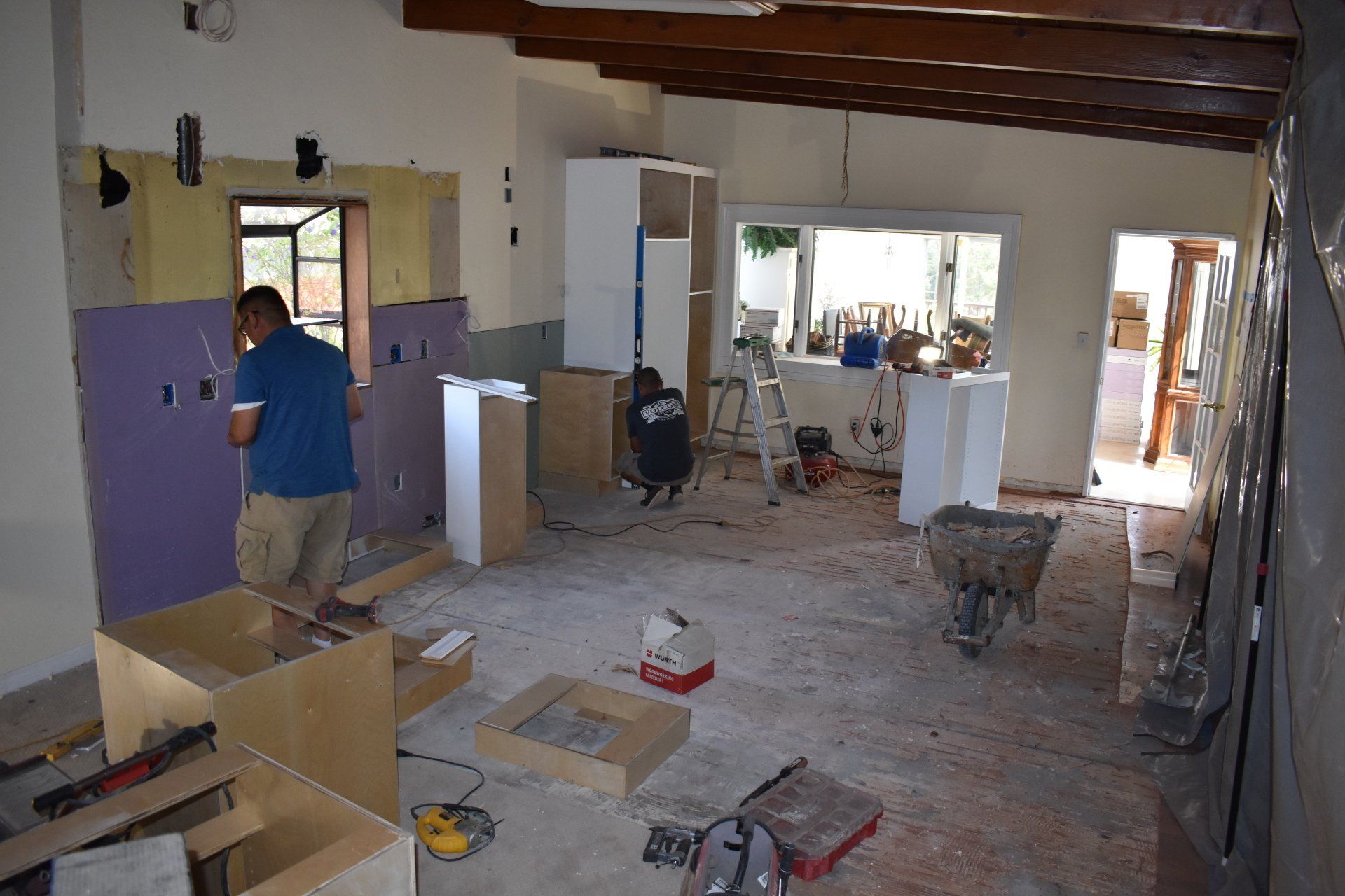 A man is working on a wall in a room that is being remodeled
