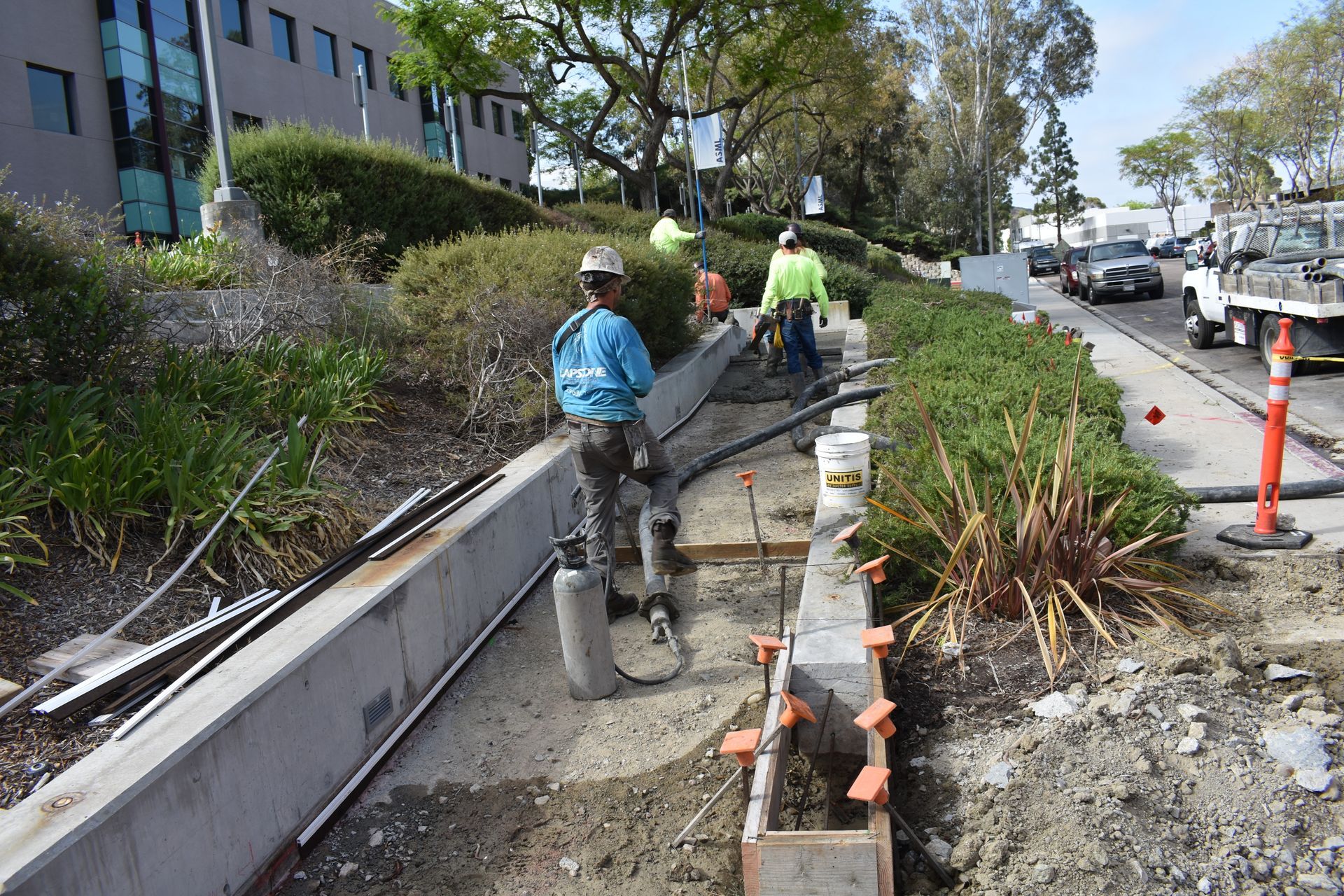 A group of construction workers are working on a sidewalk.