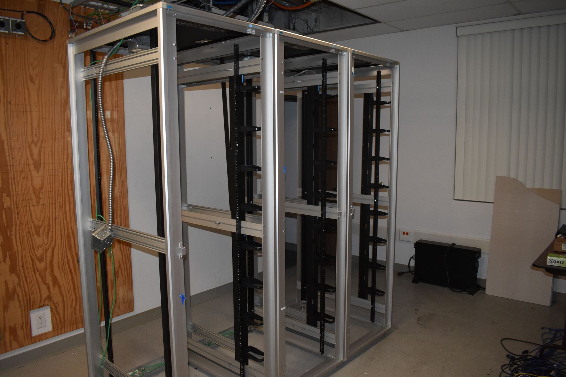 A server rack is sitting in a room next to a window.