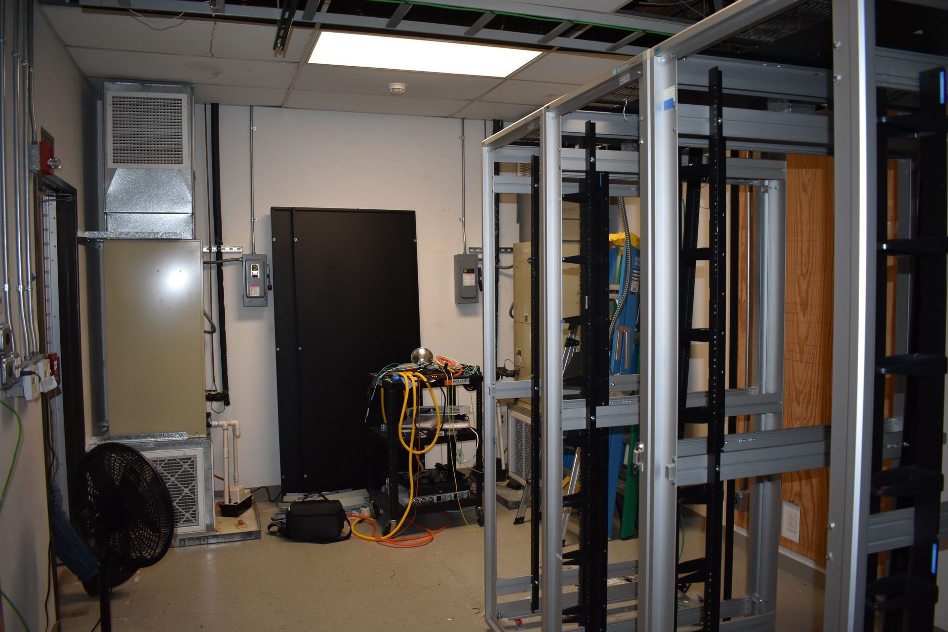 A room with a lot of racks and a fan in it.