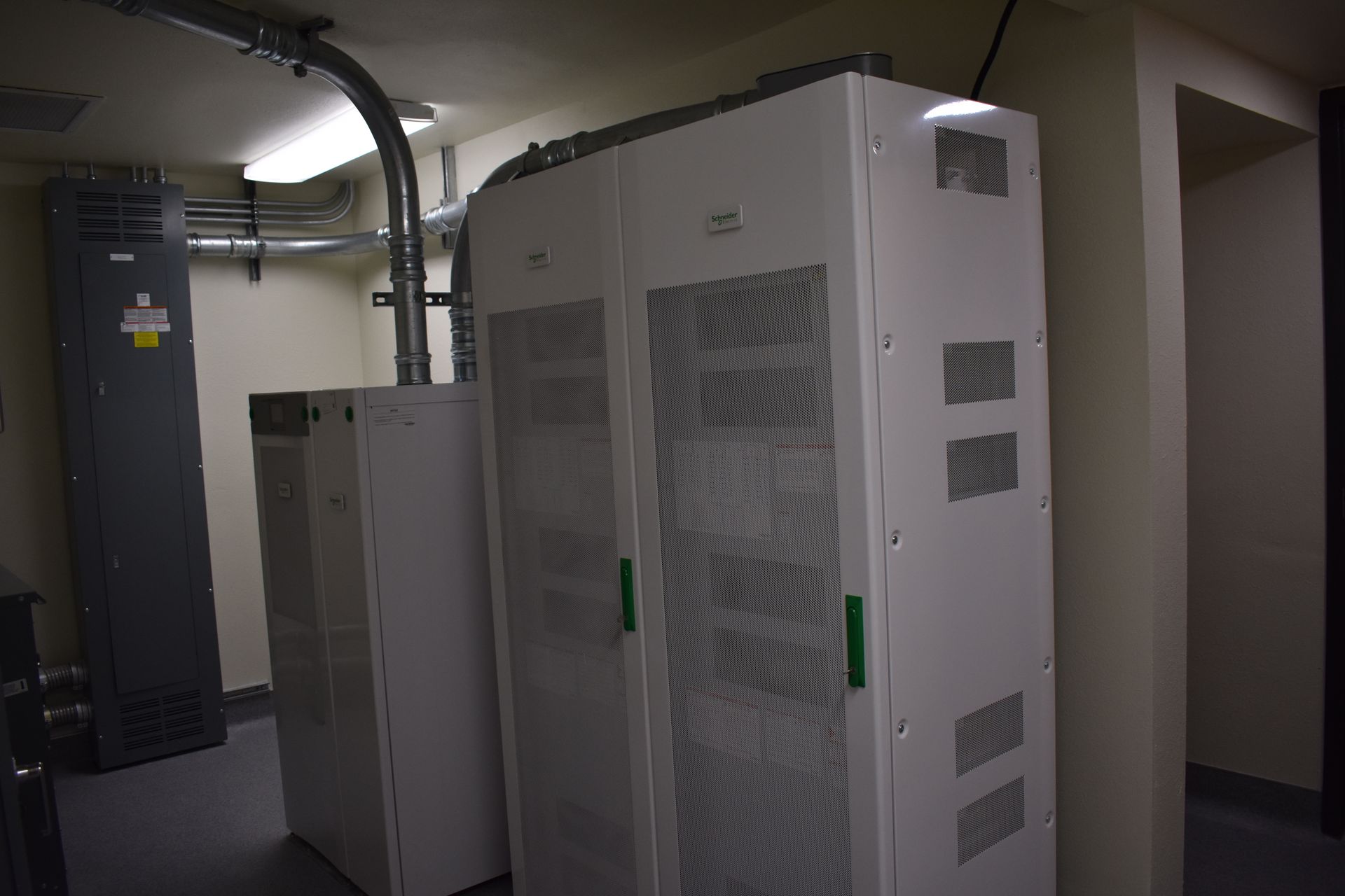 A row of white cabinets with green handles in a room.