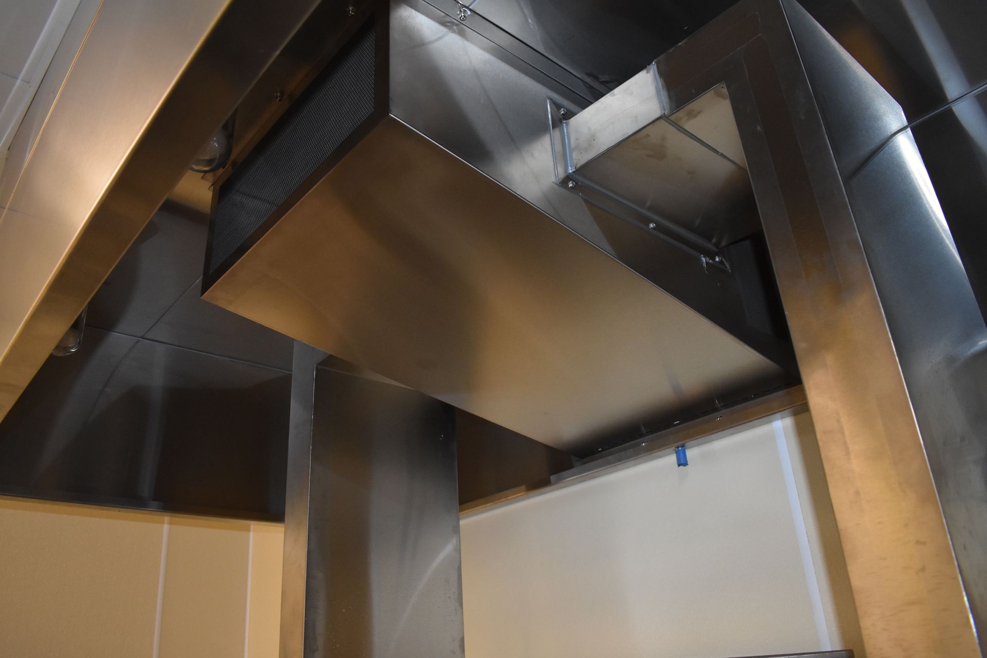 A stainless steel duct is hanging from the ceiling of a room.