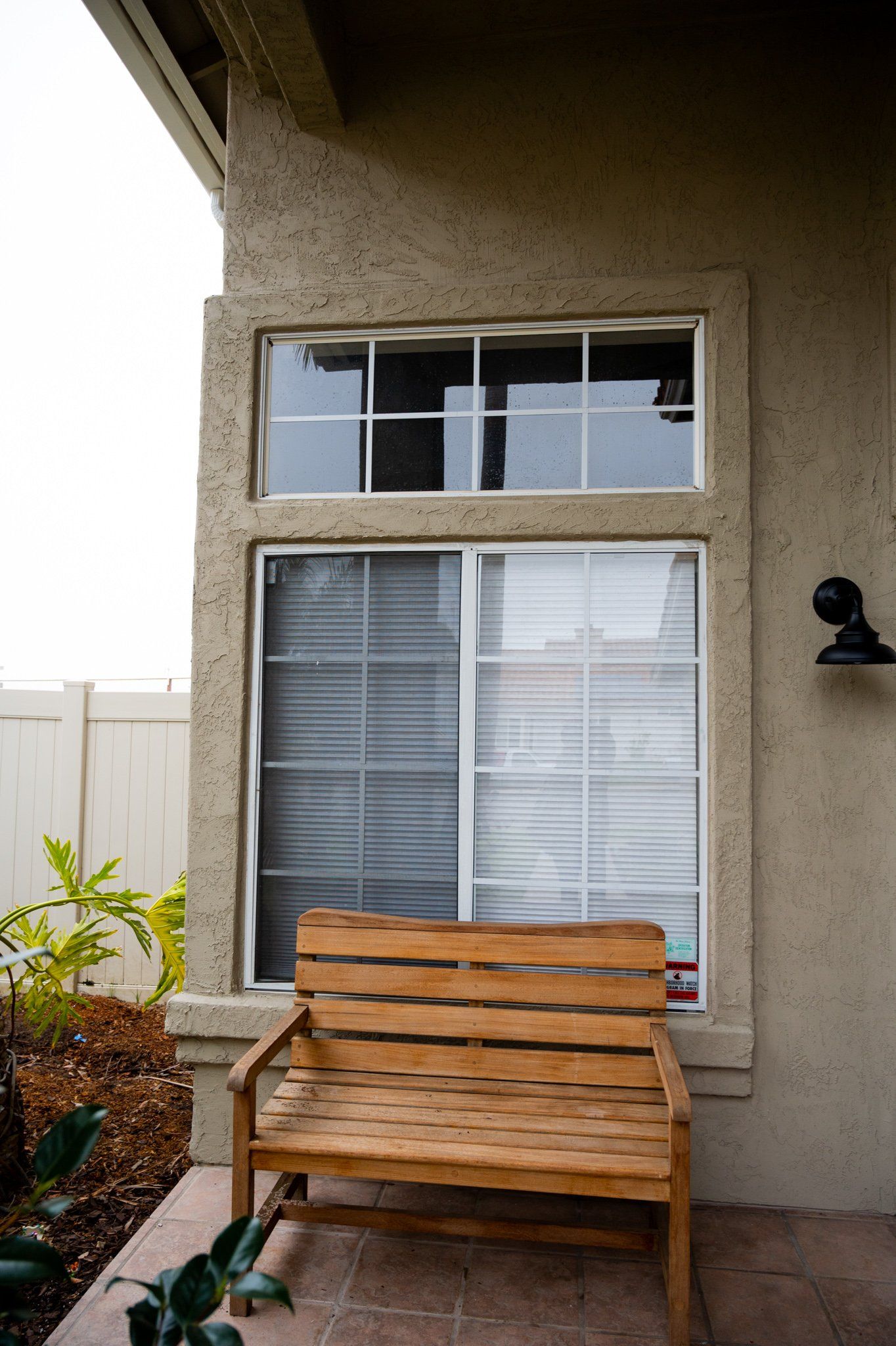 A wooden bench sits in front of a sliding glass door.