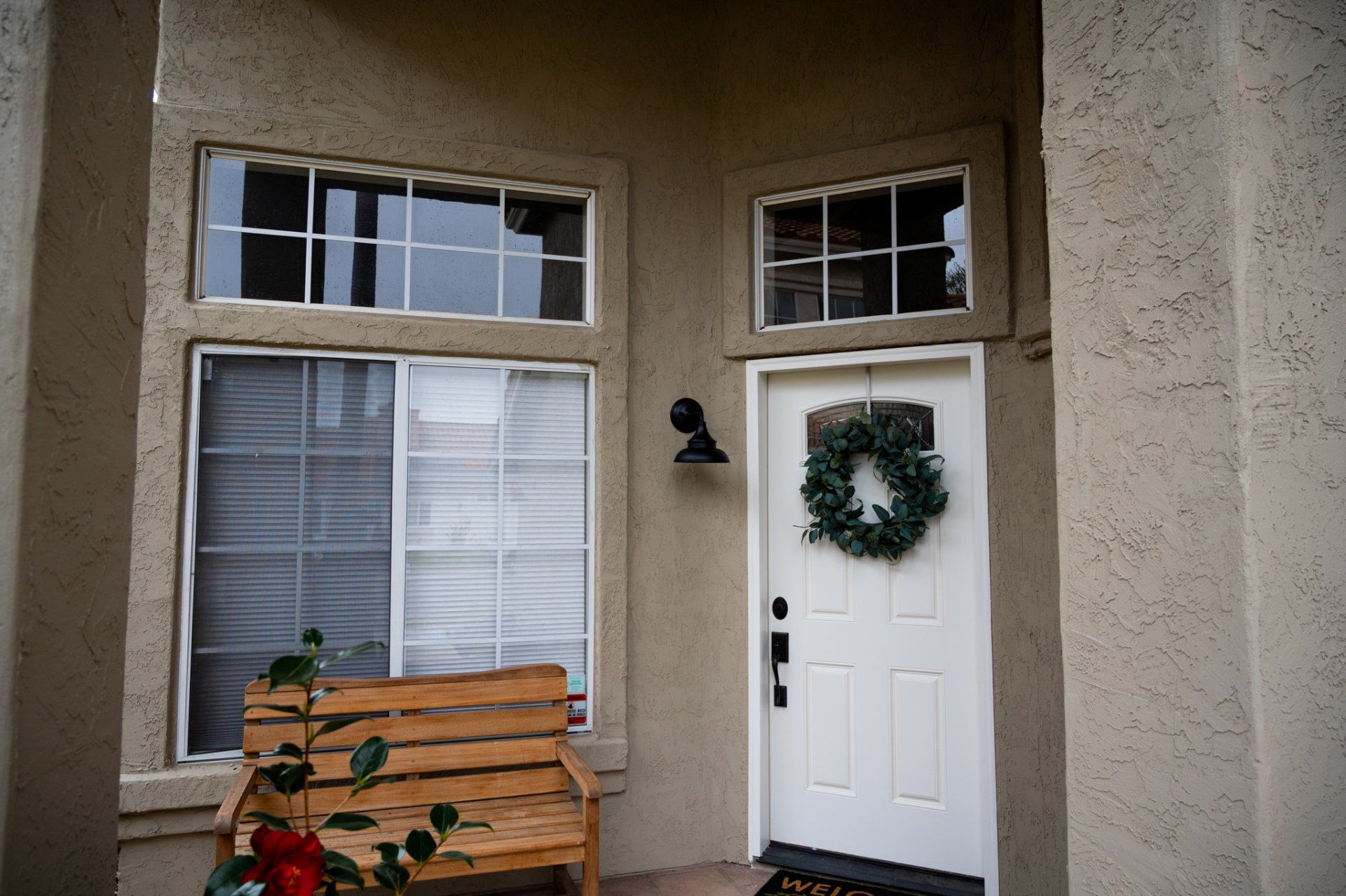 A white door with a wreath on it and a bench in front of it