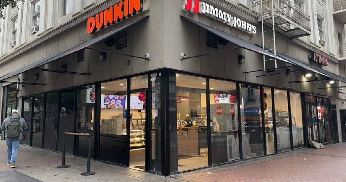A dunkin donuts restaurant is located on the corner of a city street.