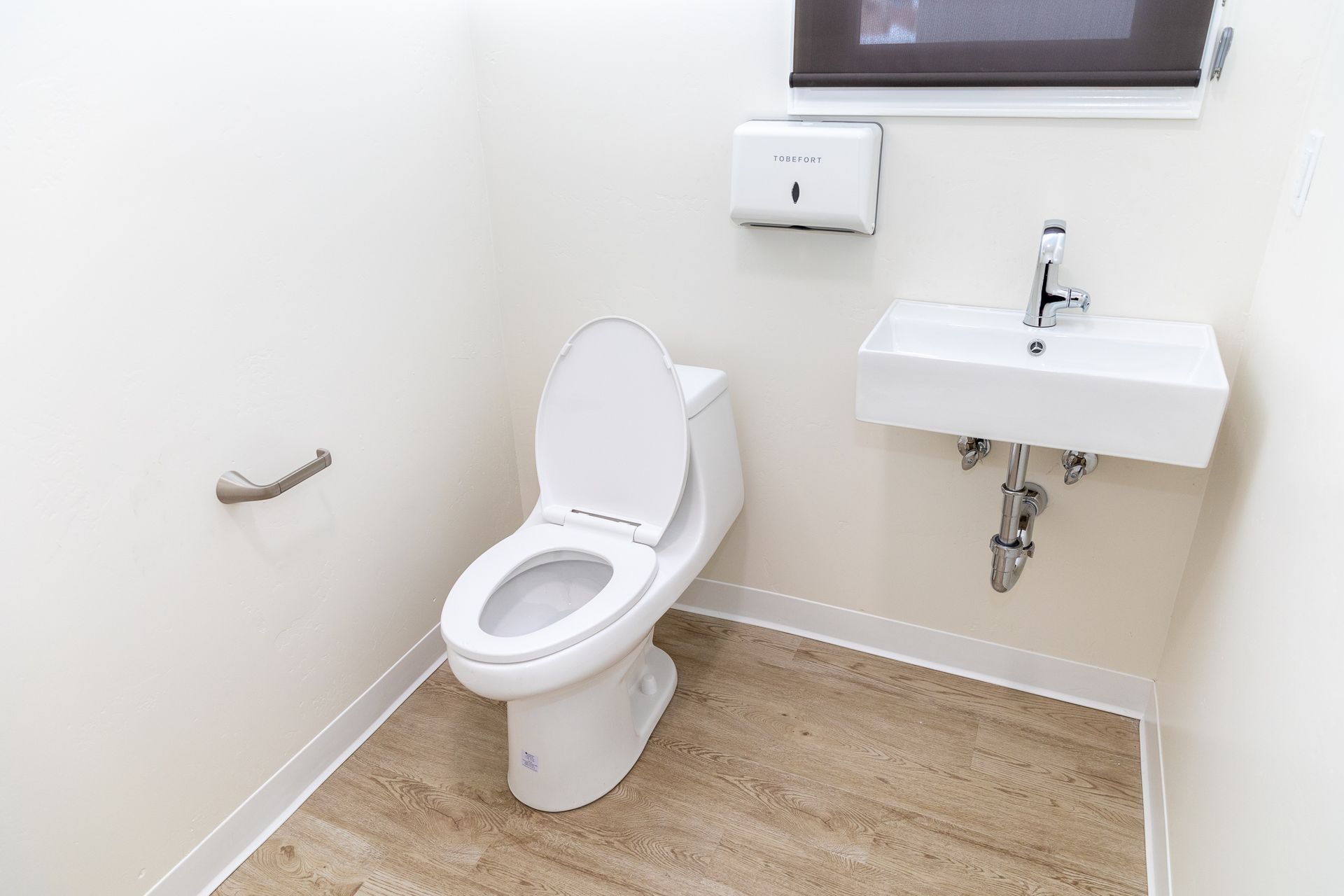 A bathroom with a toilet , sink and window.