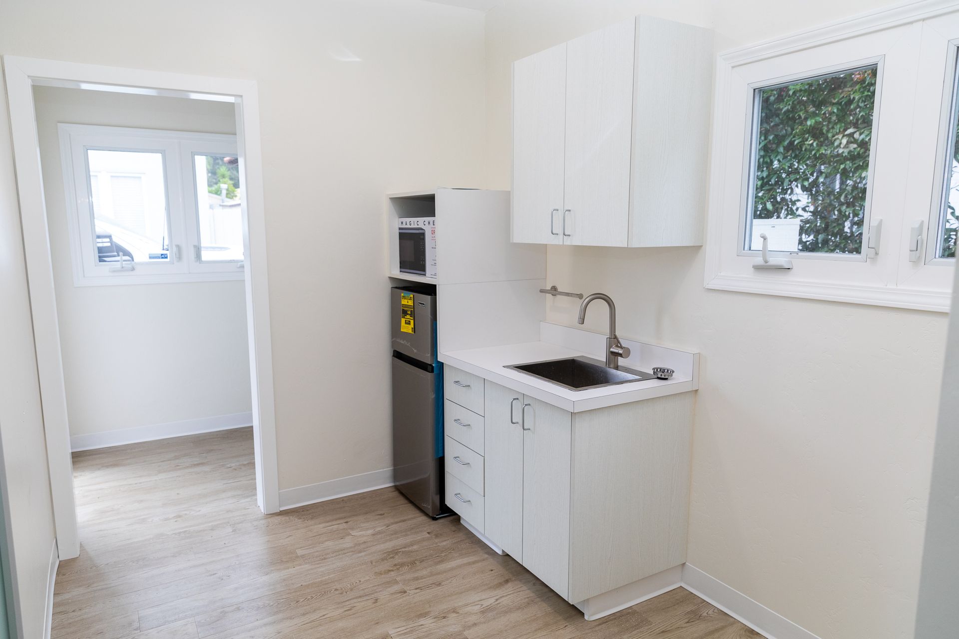 A kitchen with white cabinets , a sink , and a refrigerator.