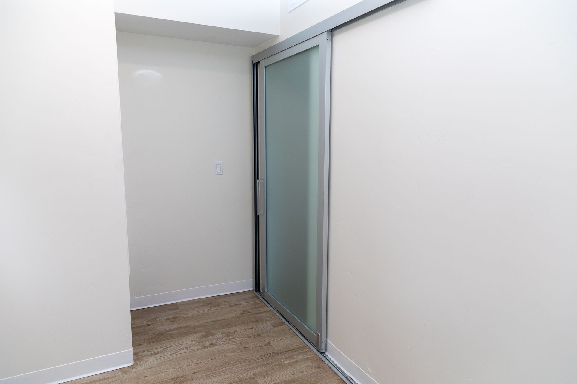 A hallway with a sliding glass door and a white wall.