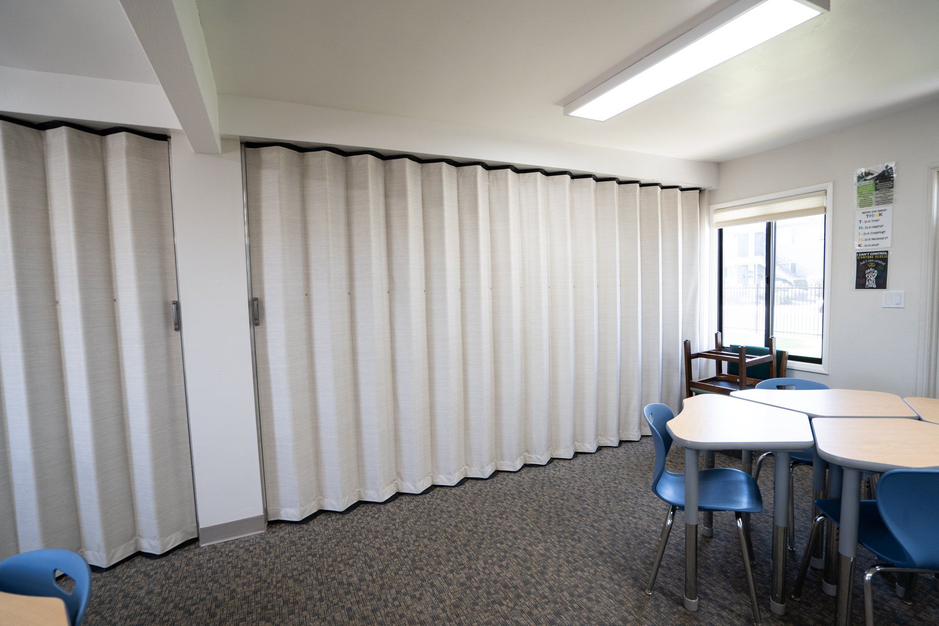 A classroom with tables and chairs and white sliding doors.