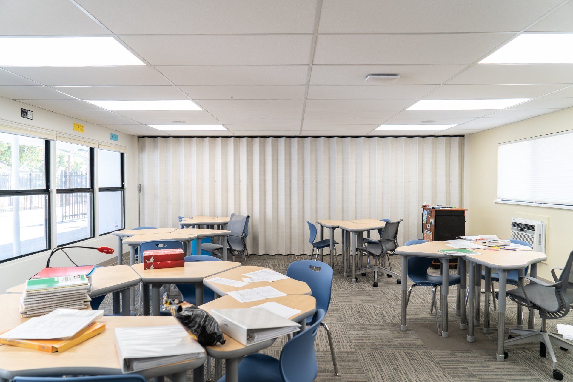A classroom with tables and chairs and a white curtain.