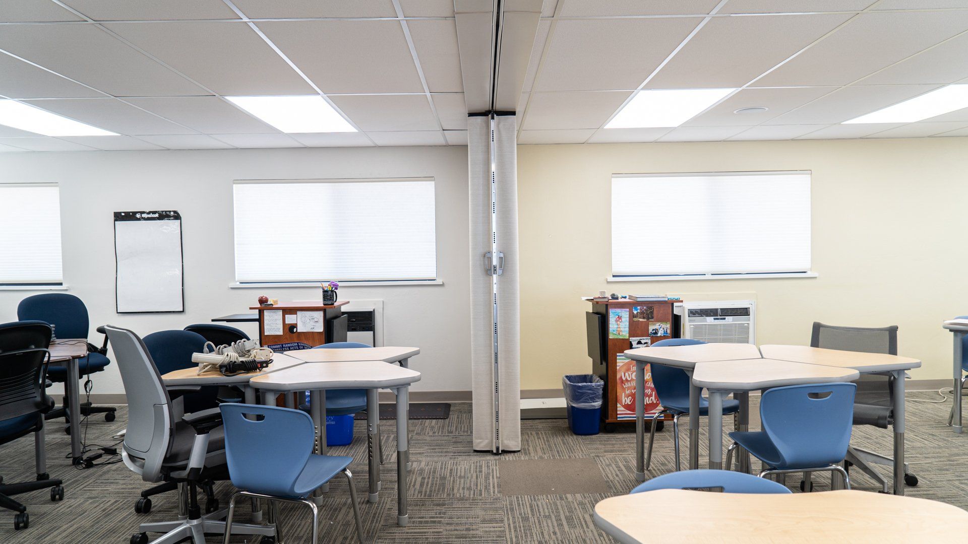 A classroom with tables and chairs and a whiteboard.