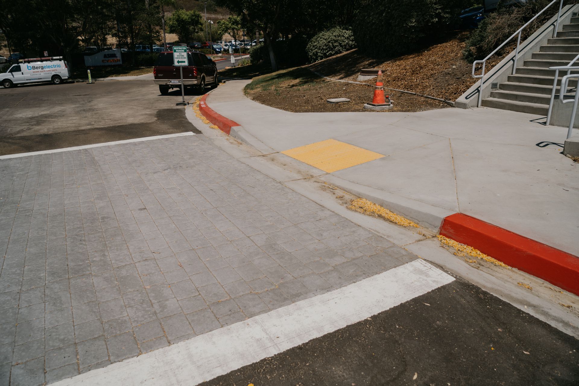 A white truck is parked on the side of the road next to a red curb.