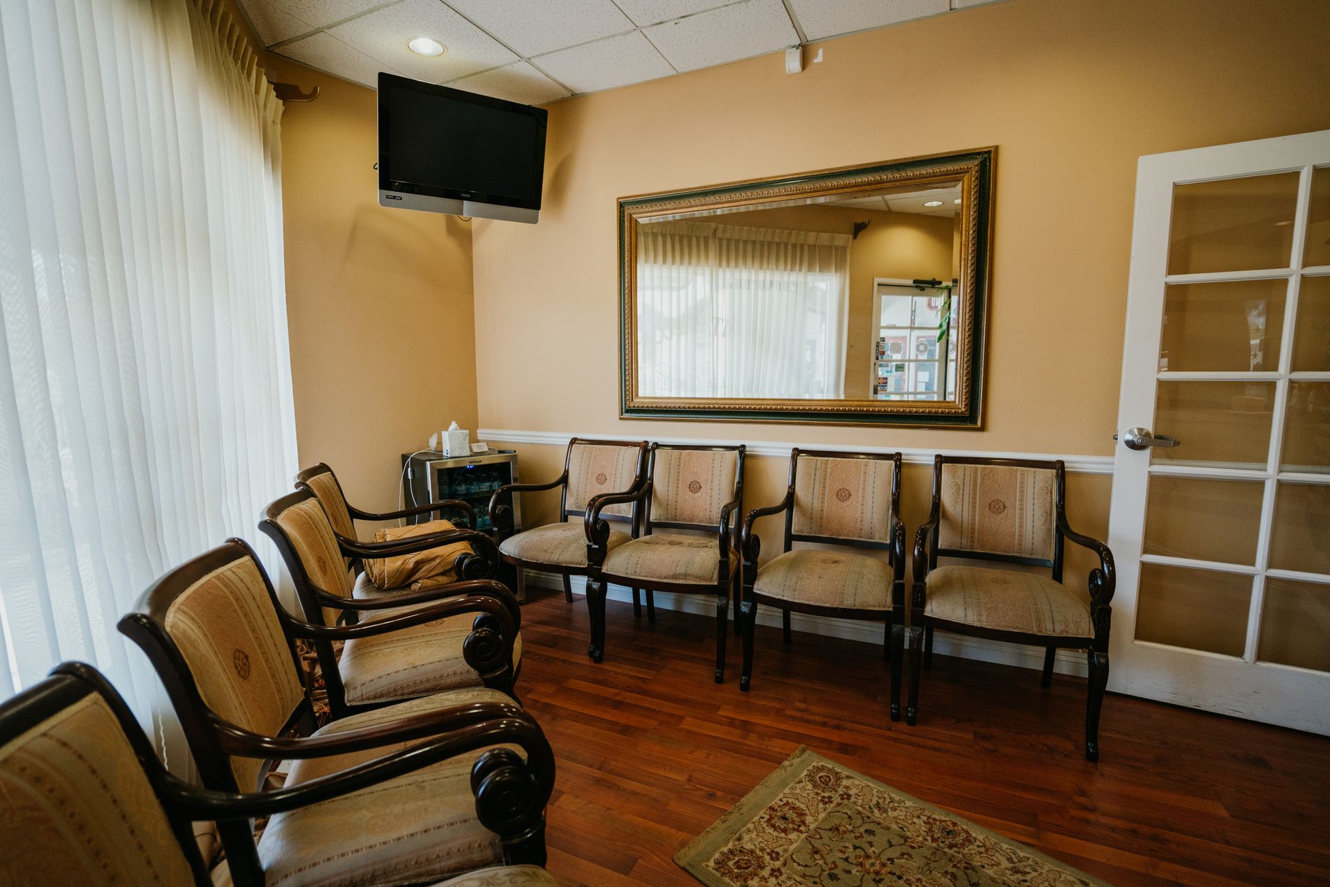 A waiting room with chairs , a television and a mirror.