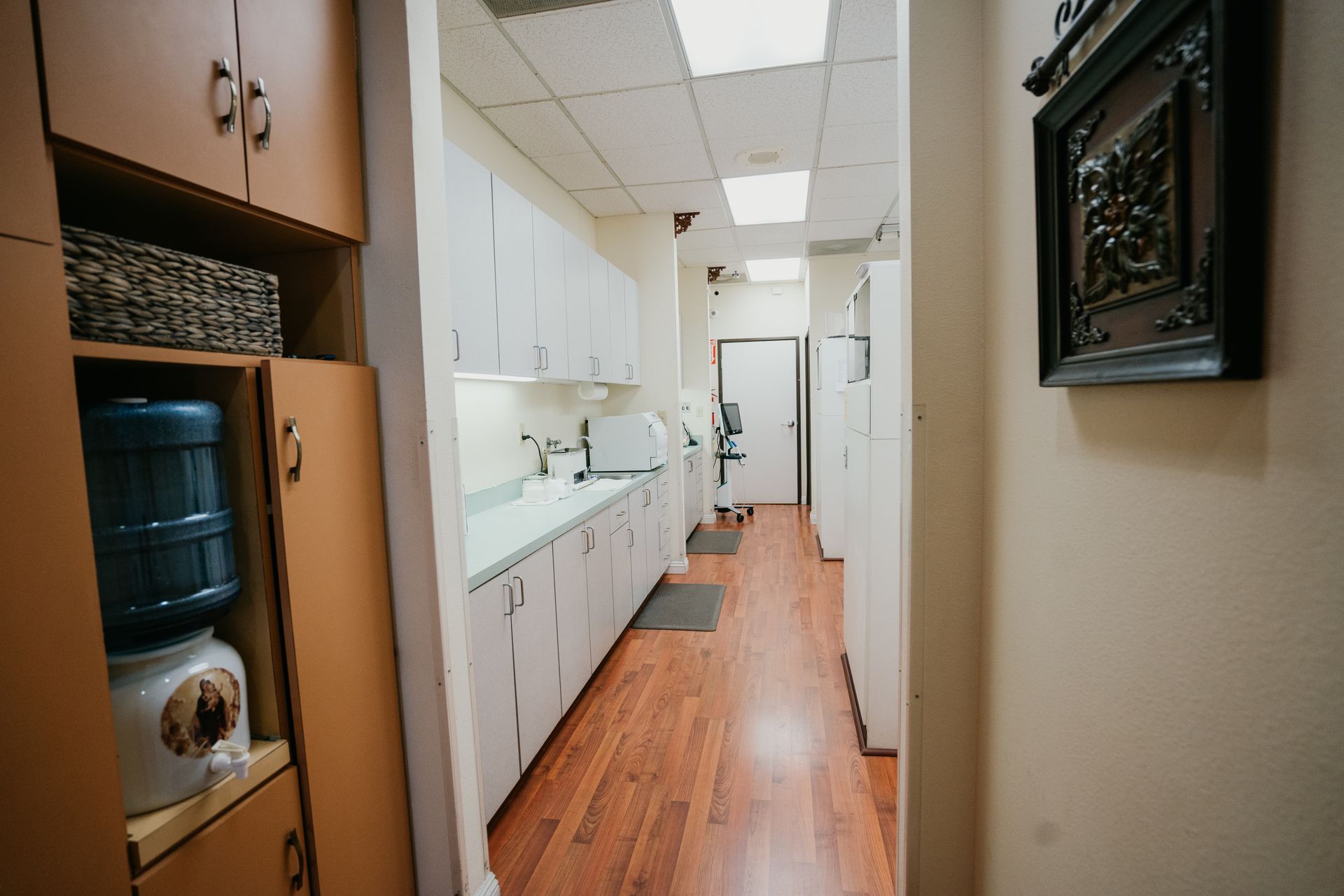 A long hallway with wooden floors and cabinets in a dental office.