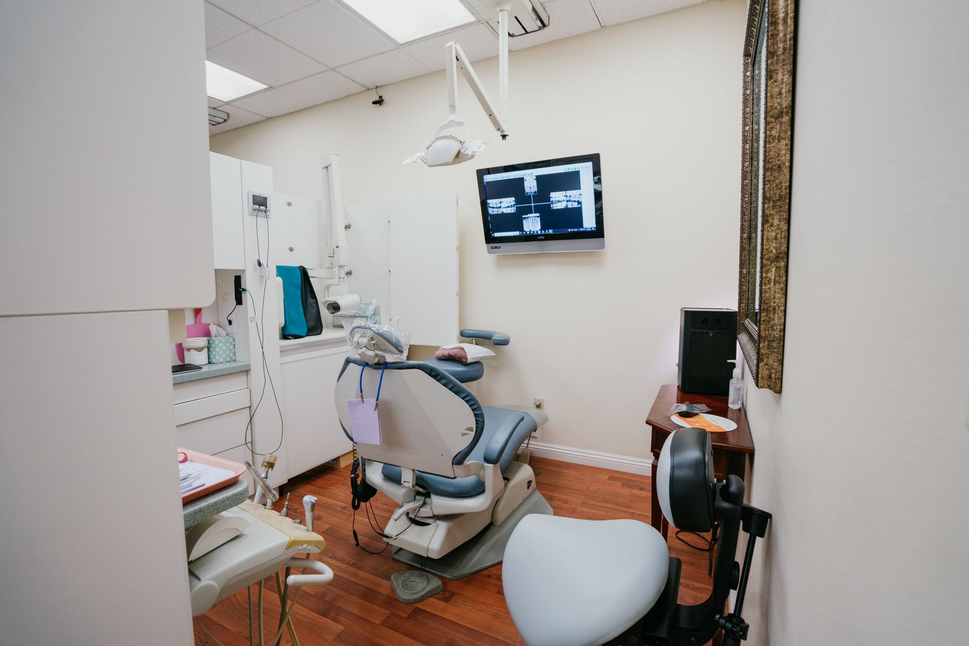 A dental office with a dental chair and a television on the wall.