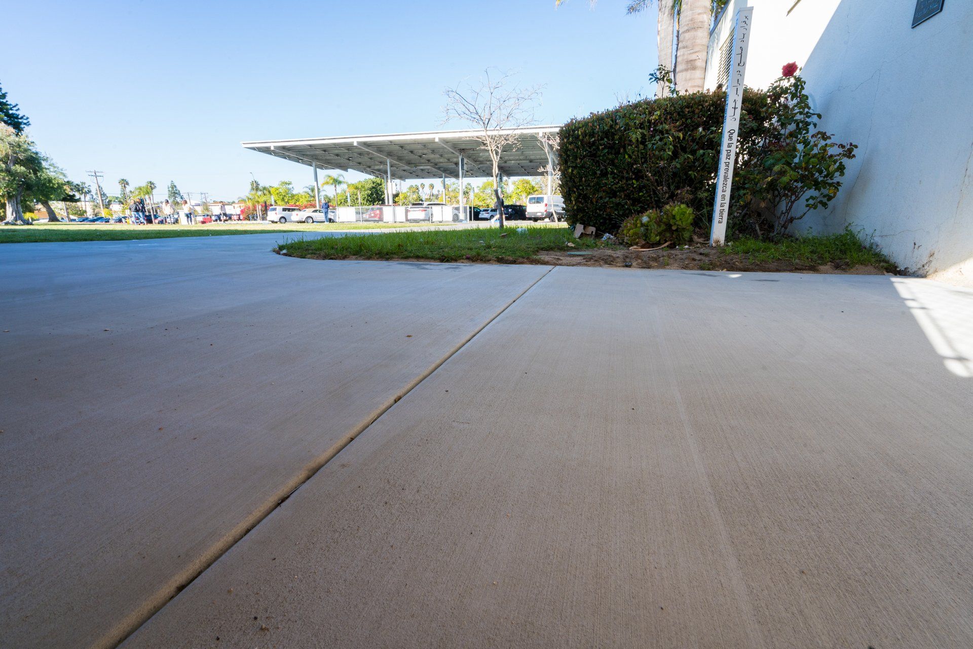 A concrete driveway with a parking lot in the background