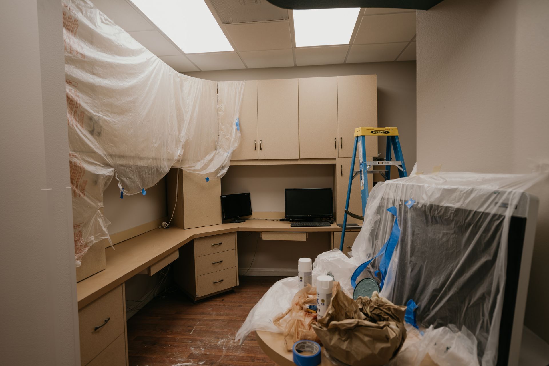 A room with a desk and a ladder covered in plastic.