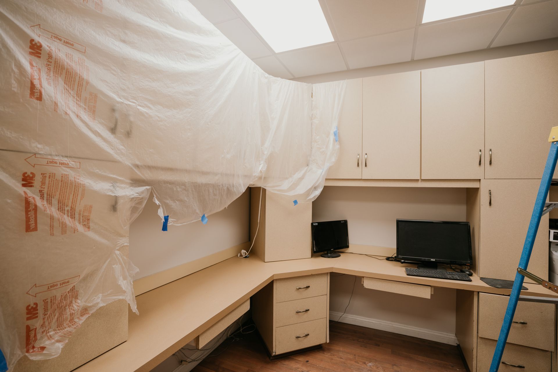 A room with a desk and a computer on it is covered in plastic.