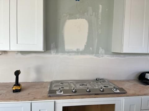 A stove top oven is sitting on top of a wooden counter in a kitchen under construction.