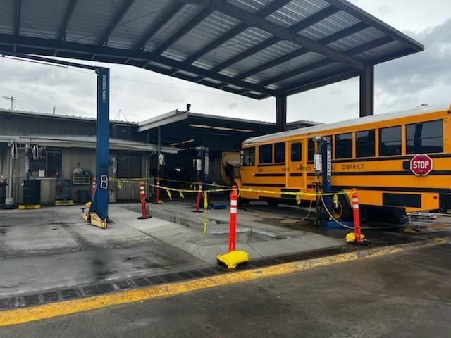A yellow school bus is parked under a canopy