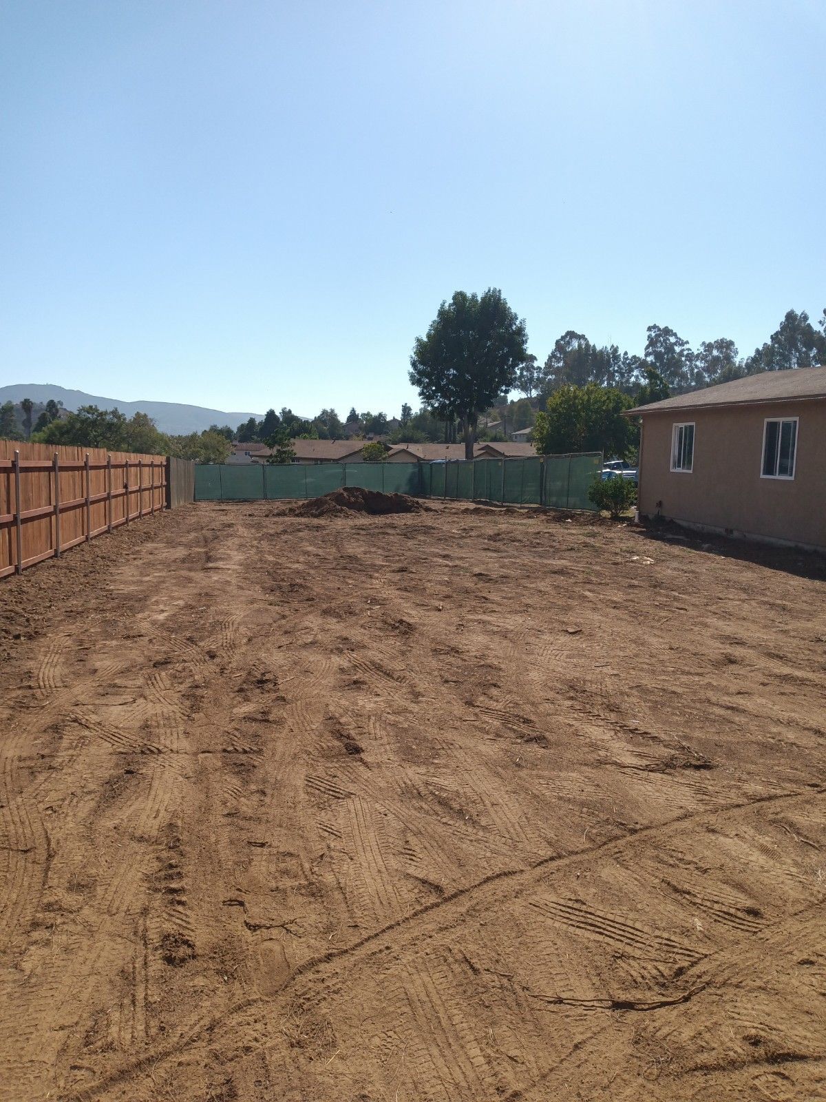 A dirt field with a house in the background
