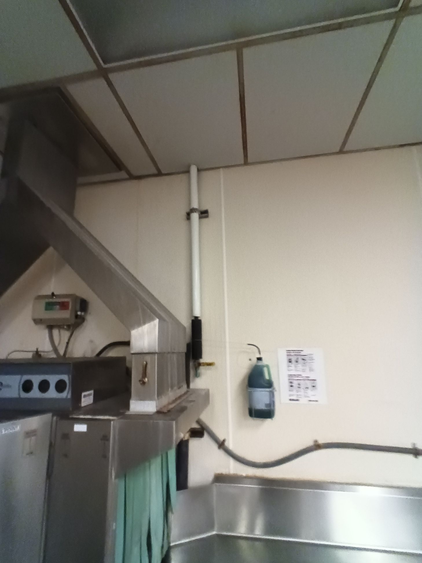 A kitchen with a stainless steel counter top and a soap dispenser on the wall