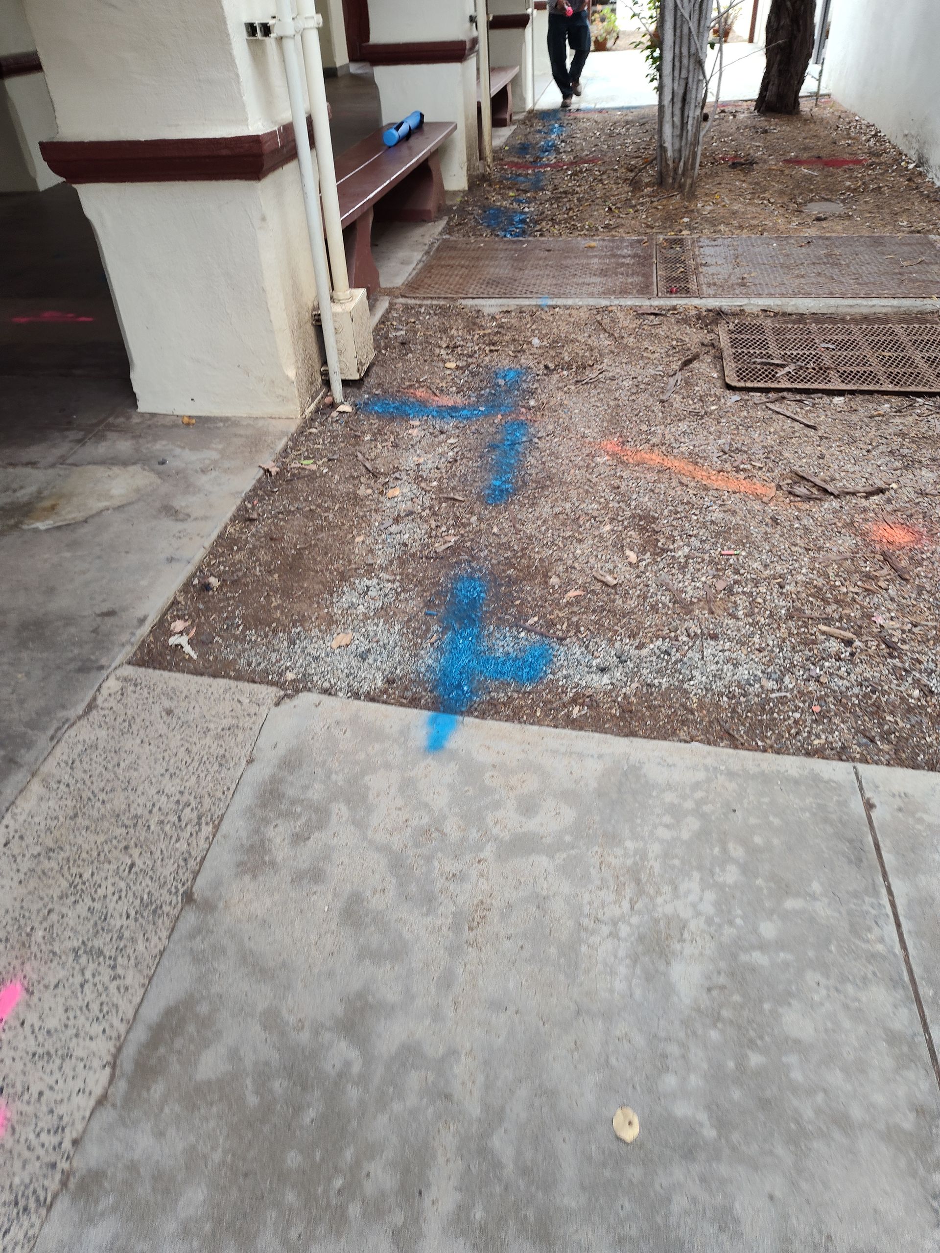 A blue cross is painted on the sidewalk in front of a building.